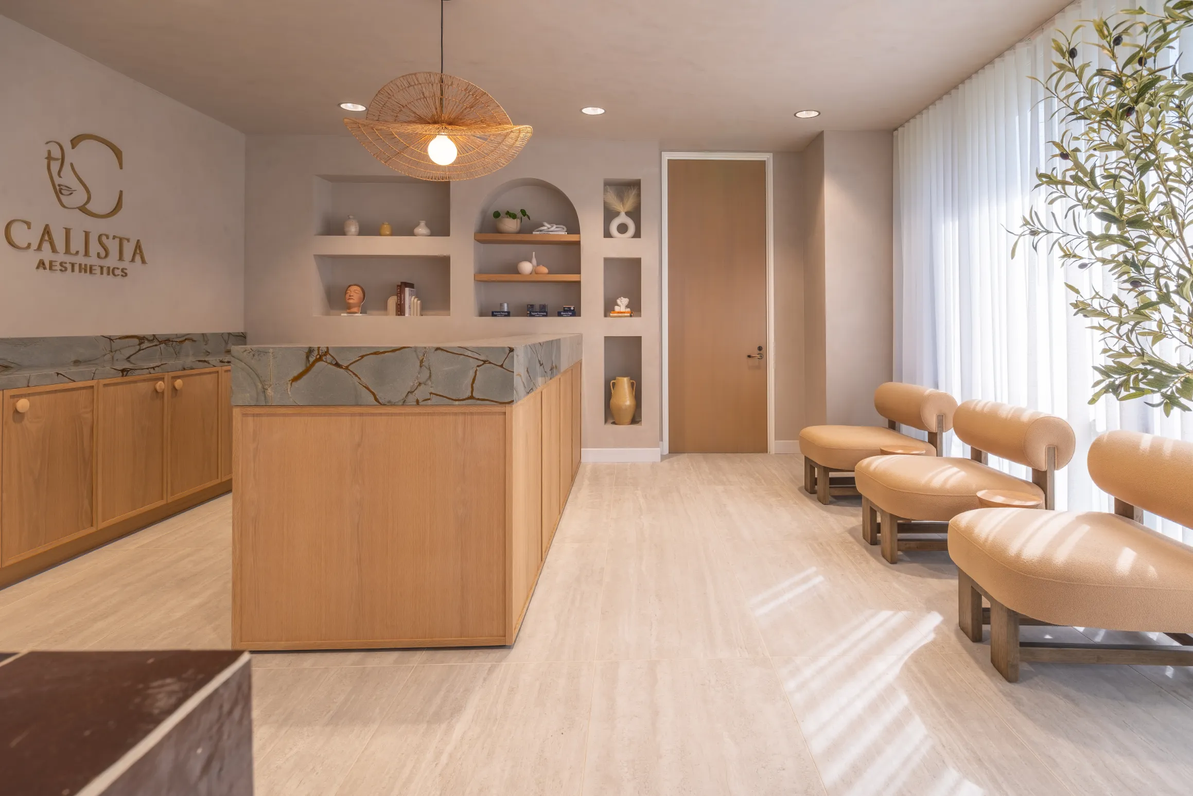 Calista reception seating area with curved beige chairs, a wooden door, and decorative wall shelving.